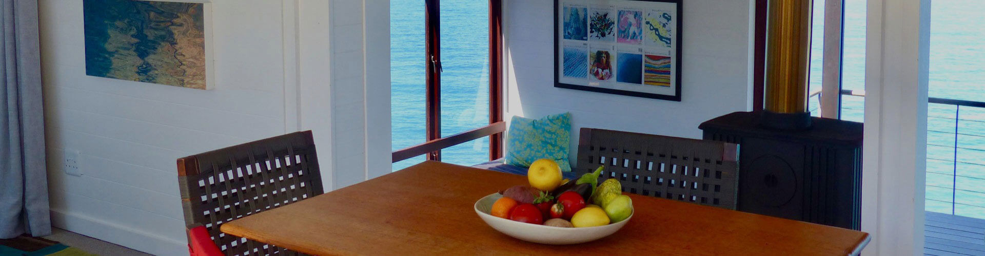 A bowl of yellow and red fruit rests on a brown table in the lounge of our Bees Knees rental villa, in the Wilderness, South Africa, where you can enjoy a magnificent ocean view right from your lounge.